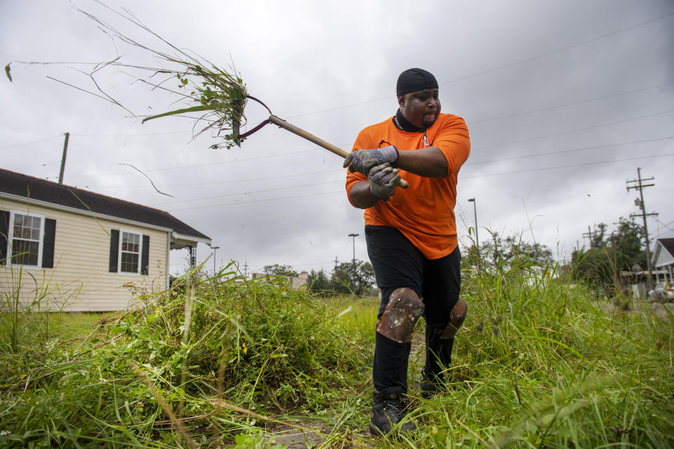 Hurricane Zeta winds make the grass that Teddy Johnson, 58, was cutting from a ditch at his family home on Flood Street in New Orleans fly in the air on Wednesday, Oct. 28, 2020. Johnson said he was quickly clearing the ditch so that any flood or rain water from the storm could drain more quickly. Johnson, who lives in Houston, Texas, moved there after Hurricane Katrina, but returns to his family's New Orleans home to help maintain it. (Chris Granger/The Times-Picayune/The New Orleans Advocate via AP)