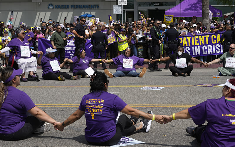 Frontline healthcare workers join hands in a circle in the middle of the road during a civil disobedience demonstration