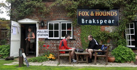 Men sit outside The Fox and Hounds pub, which houses a polling station, Christmas Common in southern England in this May 6, 2010 file photo. REUTERS/Eddie Keogh