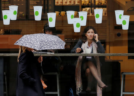 FILE PHOTO: A woman carrying an umbrella walks in the rain past a Starbucks coffee shop in London, October 8, 2012. REUTERS/Luke Macgregor/File Photo