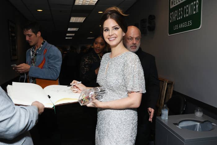 Lana smiling at a camera as she gives someone her autograph