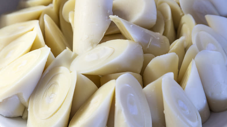 Hearts of palm chopped into discs on a wood cutting board with a knife