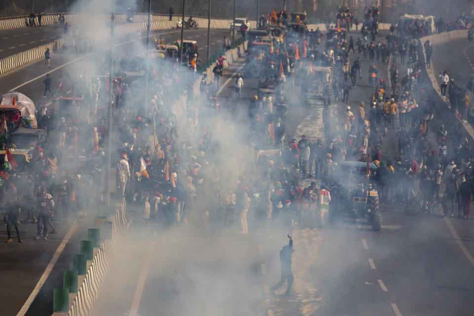 FILE - In this Tuesday, Jan. 26, 2021, file photo, protesting farmers are seen amid tear gas smoke fired by police in an attempt to stop them from marching to the capital during India's Republic Day celebrations in New Delhi, India. A sea of tens of thousands of farmers riding tractors and horses stormed India’s historic Red Fort this week, a dramatic escalation of their protests, which are posing a major challenge to Prime Minister Narendra Modi’s government. (AP Photo/Altaf Qadri, File)