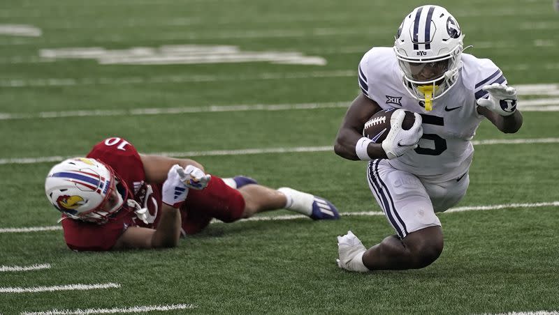 BYU wide receiver Darius Lassiter (5) is tripped up by Kansas linebacker Jayson Gilliom (10) during the second half of an NCAA college football game Saturday, Sept. 23, 2023, in Lawrence, Kan. Kansas won 38-27. (AP Photo/Charlie Riedel)