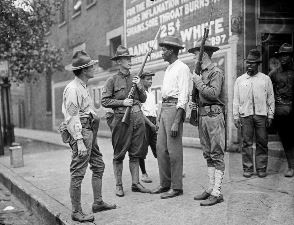 In this 1919 photo provided by the Chicago History Museum, armed National Guard and African American men stand on a sidewalk during race riots in Chicago. It was 100 years ago, in the “Red Summer” of race riots that spread across the United States, but the terror of those days still reverberates in a city that continues to grapple with segregation, housing discrimination, and deep tension between residents and police. (Chicago History Museum/The Jun Fujita negatives collection via AP)