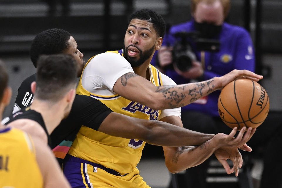 Los Angeles Lakers' Anthony Davis, right, keeps the ball from San Antonio Spurs' Rudy Gay, left rear, and Drew Eubanks during the first half of an NBA basketball game Friday, Jan. 1, 2021, in San Antonio. (AP Photo/Darren Abate)