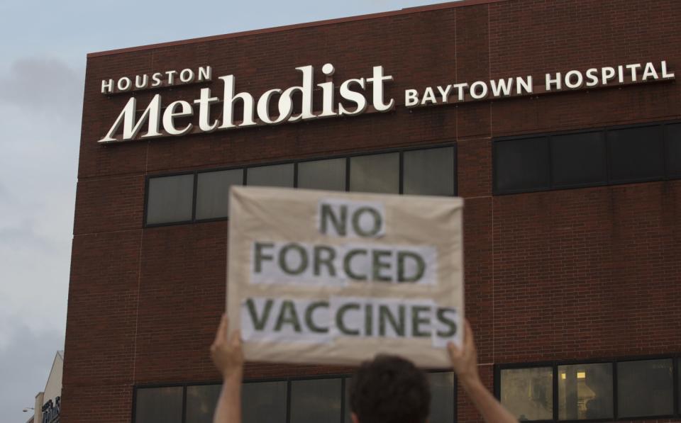 A protester holds a "No forced vaccinations" sign in front of Houston Methodist Baytown