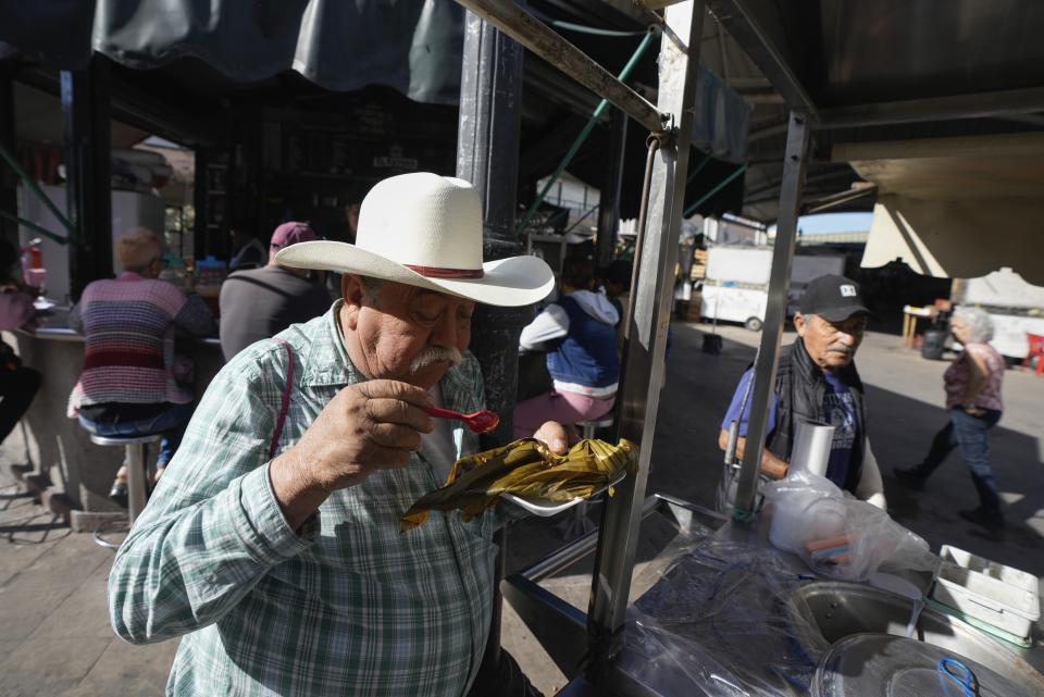 A man eats tamales at a market in Irapuato, Mexico, Friday, March 1, 2024. Presidential candidate Xóchitl Gálvez will hold her opening campaign rally on Friday in Irapuato, ahead of the June 2 general elections. (AP Photo/Fernando Llano)