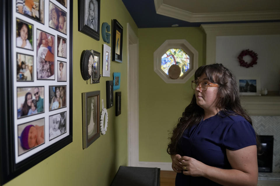 Allison Cullen, of Brockton, Mass., views a wall covered with family photo while speaking with reporters, Thursday, July, 22, 2021, at her home in Brockton. Cullen's husband Flavio Andrade Prado, a Brazilian national Prado is being held by Immigration and Customs Enforcement, or ICE, at the Plymouth County House of Corrections. Cullen, a mother of two, says she and her children haven't been able to visit her husband since before the pandemic. (AP Photo/Steven Senne)