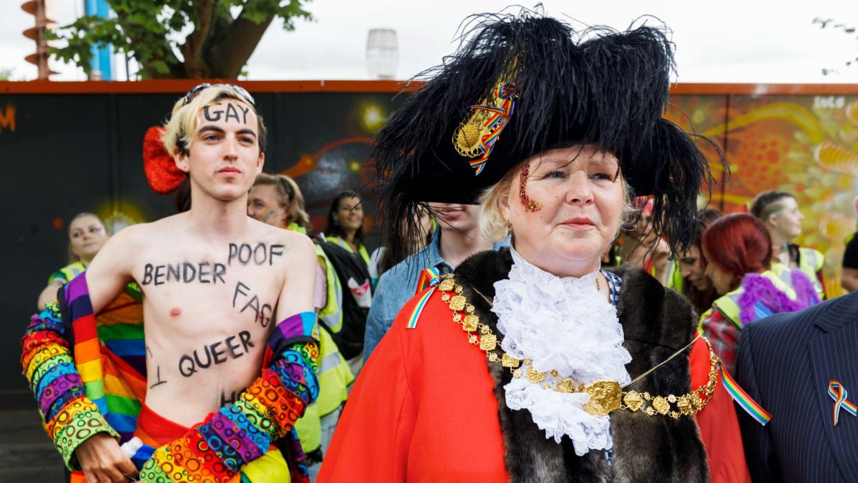  Half naked man walking behind a ceremonial mayor at a Pride march 