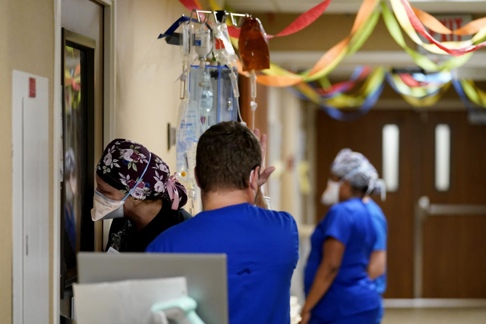 A member of the medical staff wipes his brow as another looks into a COVID -19 patient's room in an intensive care unit at the Willis-Knighton Medical Center in Shreveport, La., Wednesday, Aug. 18, 2021. (AP Photo/Gerald Herbert)