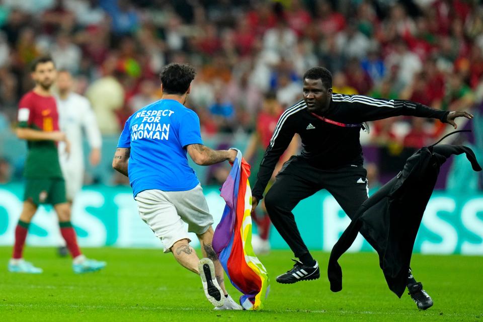 A pitch invader runs across the field with a rainbow flag during the World Cup group H soccer match between Portugal and Uruguay, at the Lusail Stadium in Lusail, Qatar, Monday, Nov. 28, 2022. (AP Photo/Petr David Josek)