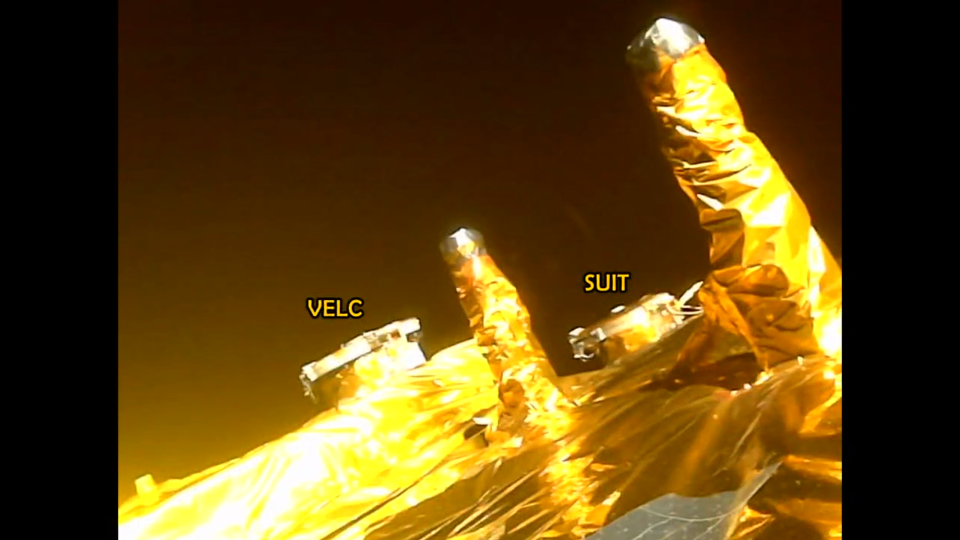 a golden spacecraft visible in space with some of the instruments labeled in text