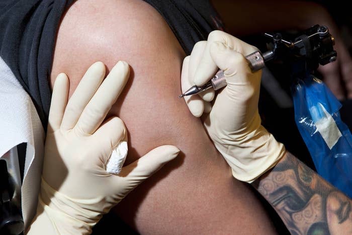 tattoo artist holding their tattoo gun to a client's leg