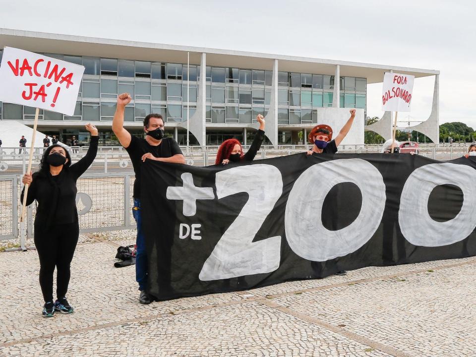 brazlian protesters holding up signs demanding vaccines