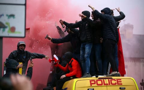 Fans stand on top of a police van amid smoke from flares outside the stadium before the Champions League semi-final - Credit: Dave Thompson/AP