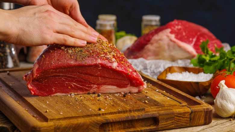 Hands rubbing seasoning on steak