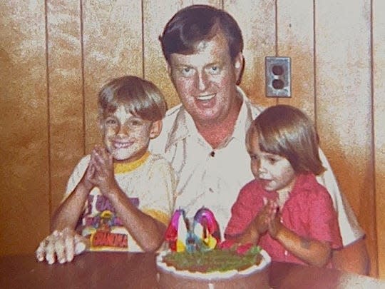 Nicole Johnson with her brother and grandfather in front of a birthday cake.