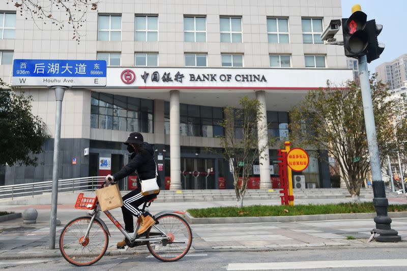 Woman wearing a face mask rides a shared bicycle past a Bank of China branch in Wuhan, the epicentre of the novel coronavirus outbreak