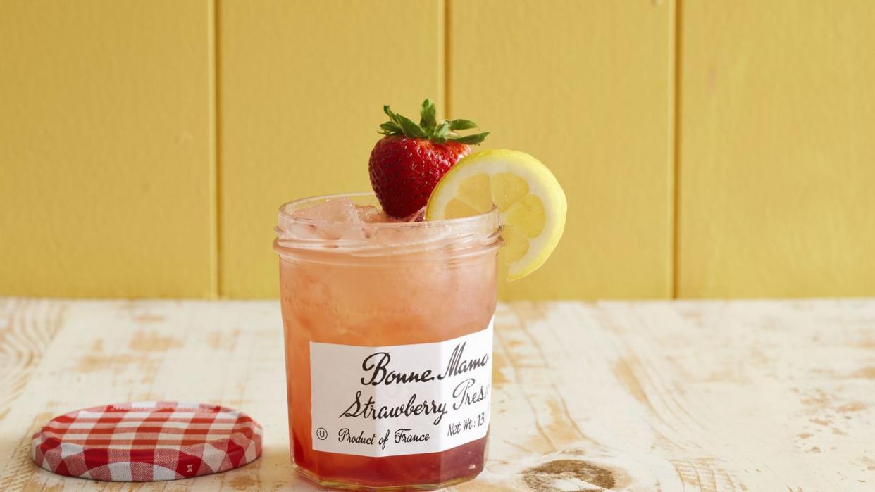 a strawberry jam jar with a drink in it and a lemon and strawberry garnish on the side