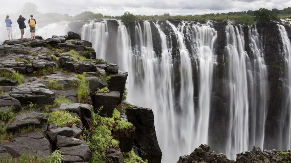 People stand on the edge of Victoria Falls.