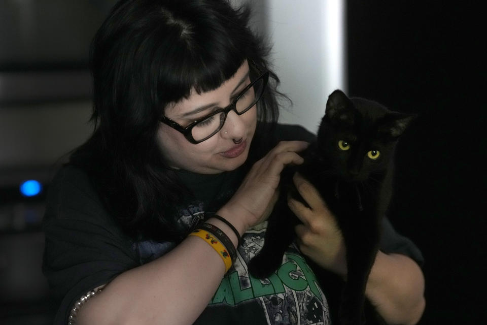 Beka Favela pets her cat Celine at her Westmont, Ill., apartment Tuesday, June 20, 2023. After a payment pause that has lasted more than three years, more than 40 million student loan borrowers will be on the hook for payments starting in the fall. (AP Photo/Charles Rex Arbogast)