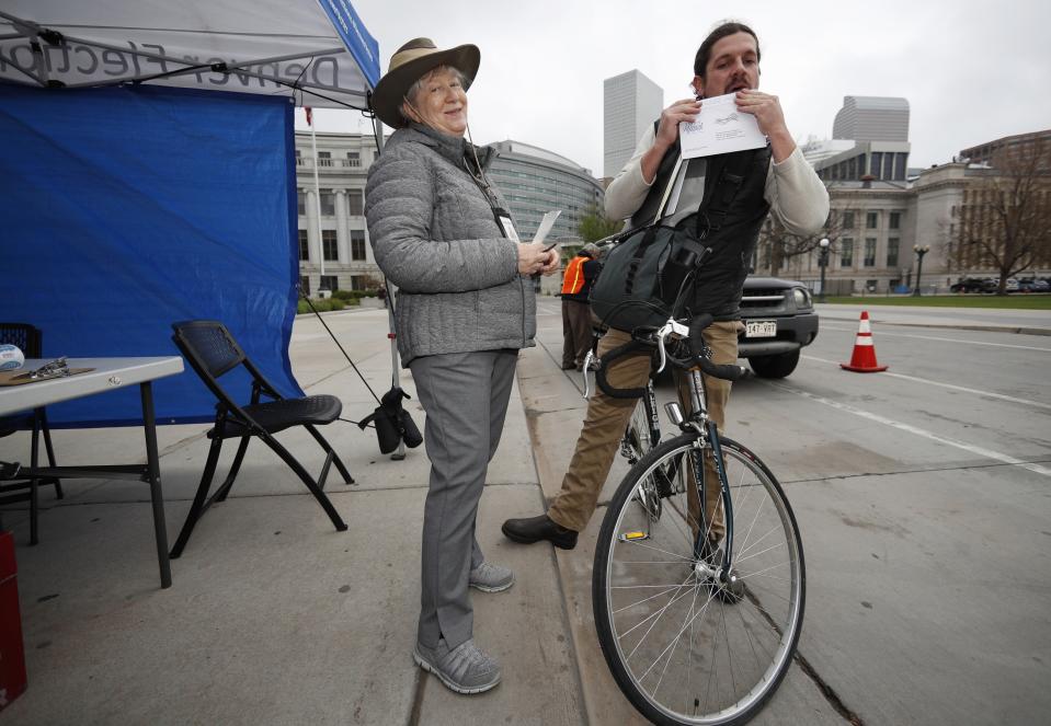 Election judge Susan Morrison, left, laughs as Axie Blundon of Denver licks the seal on the envelope containing his ballot as he drops it off at the Denver Electoral Commission Tuesday, May 7, 2019, in Denver. Voters could make Denver the first U.S. city to decriminalize the use of psilocybin, the psychoactive substance in "magic mushrooms" if the measure passes. (AP Photo/David Zalubowski)