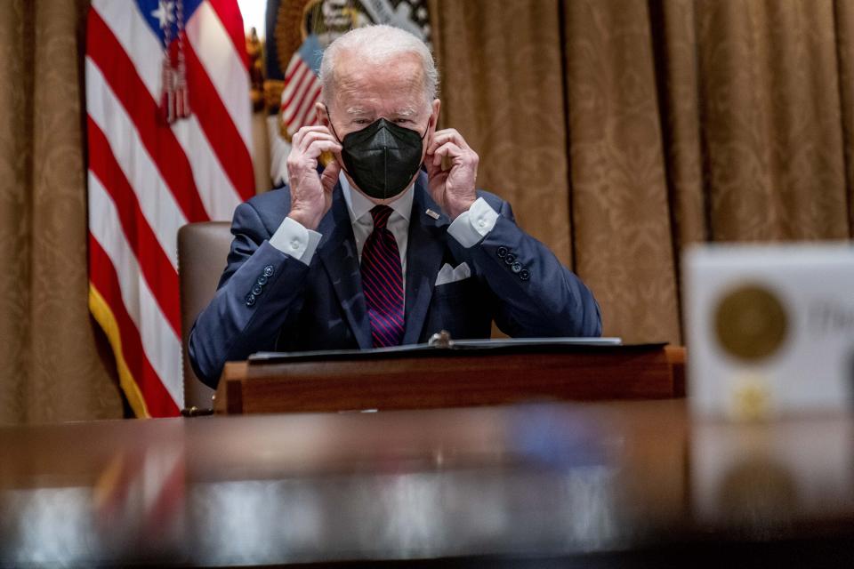 President Joe Biden puts on his mask during a meeting with members of the Infrastructure Implementation Task Force to discuss the Bipartisan Infrastructure Law, in the Cabinet Room of the White House in Washington, Thursday, Jan. 20, 2022. (AP Photo/Andrew Harnik)