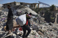 People search through the rubble of collapsed buildings where a newborn girl was found in the town of Jinderis, Aleppo province, Syria, Tuesday, Feb. 7, 2023. Residents in the northwest Syrian town discovered the crying infant, whose mother gave birth to her while buried underneath the rubble of a five-story apartment building leveled by this week's devastating earthquake, relatives and a doctor say. (AP Photo/Ghaith Alsayed)