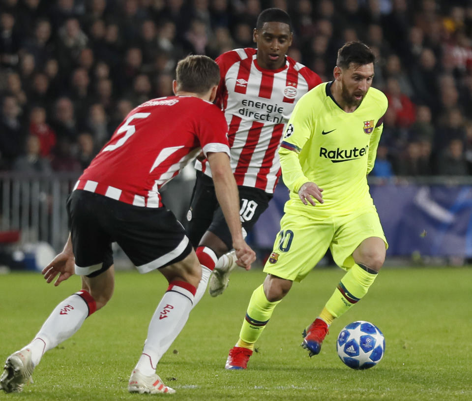 Barcelona forward Lionel Messi passes PSV's Pablo Rosario, rear, and PSV's Daniel Schwaab, left, during a Group B Champions League soccer match between PSV Eindhoven and Barcelona at the Philips stadium in Eindhoven, Netherlands, Wednesday, Nov. 28, 2018. (AP Photo/Peter Dejong)