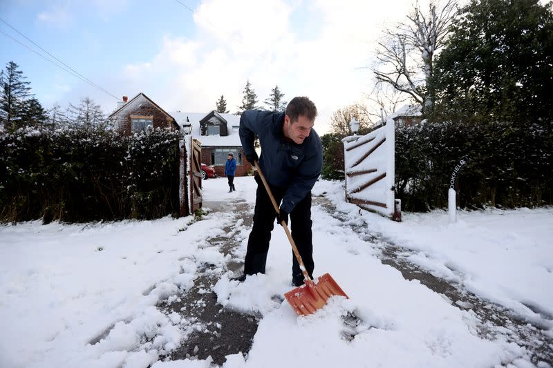 A man clears his driveway of snow that fell overnight from Storm Arwen, in Leek