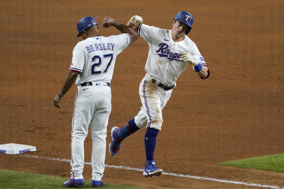 Texas Rangers third base coach Tony Beasley (27) and Nick Solak, right, celebrate as Solak jogs home after hitting a solo home run off New York Yankees starting pitcher Jameson Taillon during the fifth inning of a baseball game in Arlington, Texas, Tuesday, May 18, 2021. (AP Photo/Tony Gutierrez)