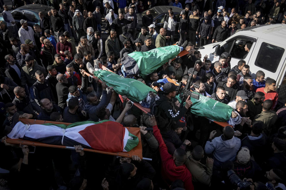 Mourners carry the bodies of six Palestinians, some are draped in the Hamas flags during their funeral in the West Bank city of Jenin on Sunday, Jan. 7, 2024. Six Palestinians and a member of Israel's paramilitary border police were killed in confrontations in a hot spot of violence in the Israeli-occupied West Bank, the Palestinian Health Ministry and the Israeli military said Sunday. (AP Photo/Majdi Mohammed)