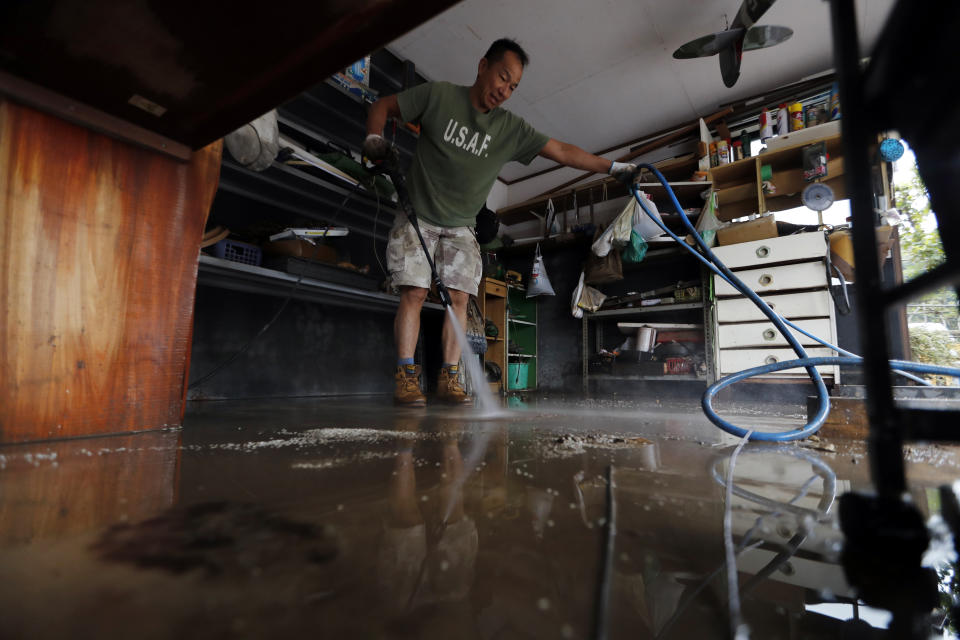 A volunteer helps clean up from Typhoon Hagibis Monday, Oct. 14, 2019, in Kawagoe City, Japan. Rescue crews in Japan dug through mudslides and searched near swollen rivers Monday as they looked for those missing from Hagibis that left as dozens dead and caused serious damage in central and northern Japan. (AP Photo/Eugene Hoshiko)