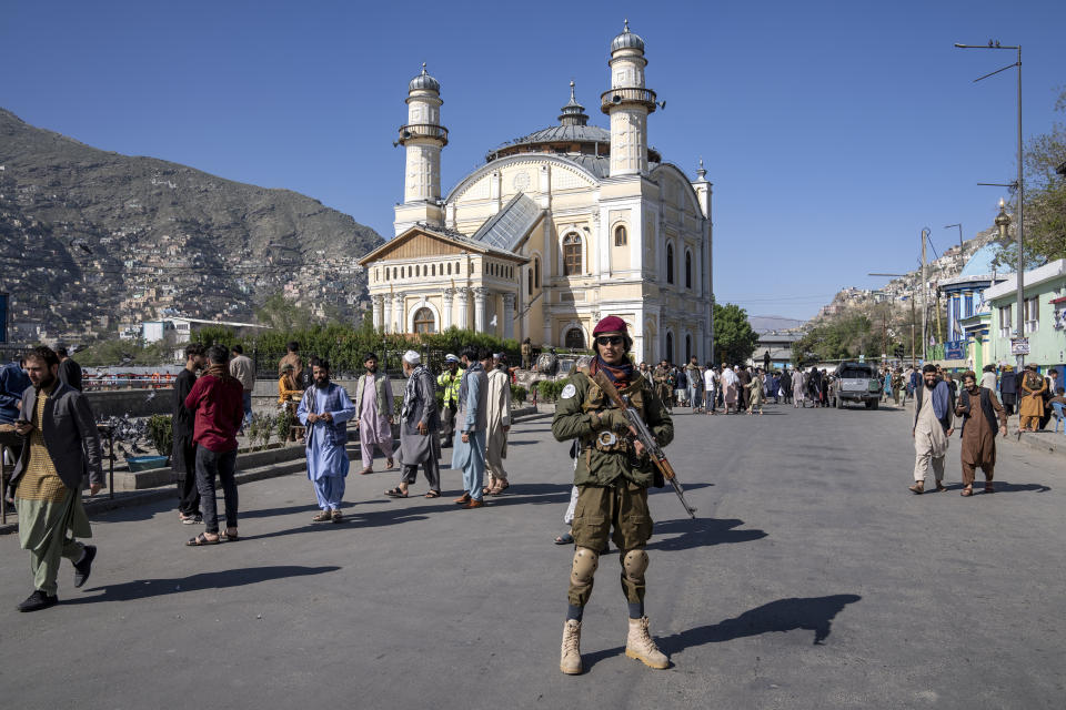 A Taliban fighter stands guard as Afghan people attend Eid al-Fitr prayers, marking the end of the holy fasting month of Ramadan, in Kabul, Afghanistan, Friday, April 21, 2023. (AP Photo/Ebrahim Noroozi)