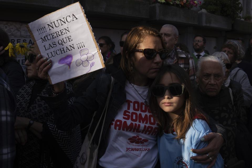 A woman holds a sign that reads in Spanish; "Those who fight never die," during the burial service of Amelia Sanjurjo at La Teja cemetery in Montevideo, Uruguay, Thursday, June 6, 2024. The Uruguayan Prosecutor’s Office confirmed that the human remains found in June 2023 at the 14th Battalion of the Uruguayan Army belong to Sanjurjo, a victim of the 1973-1985 dictatorship who was 41 years old and pregnant at the time of her disappearance. (AP Photo/Matilde Campodonico)