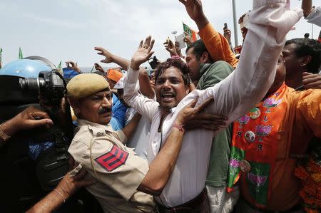 A policeman holds back a supporter of Hindu nationalist Narendra Modi, prime ministerial candidate for India's main opposition Bharatiya Janata Party (BJP), as they cheer after Modi's arrival at the airport in New Delhi May 17, 2014. REUTERS/Adnan Abidi