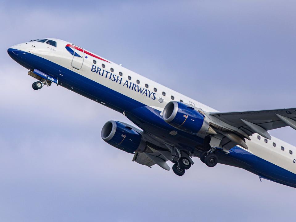 A British Airways Embraer ERJ-190, painted blue and white, departing from Amsterdam.