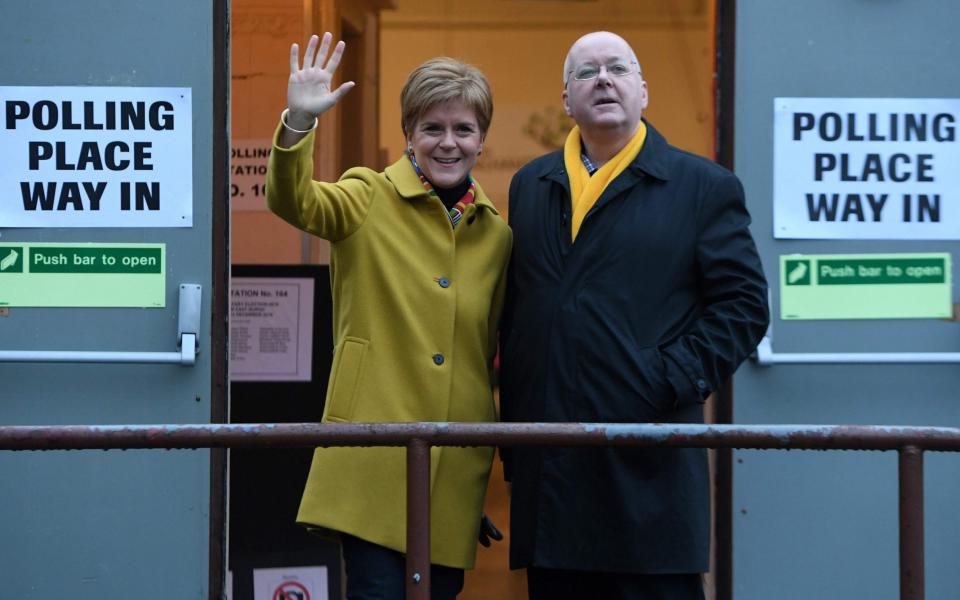 Scotland's First Minister and leader of the Scottish National Party (SNP), Nicola Sturgeon, stands with her husband husband Peter Murrell as they stand outside a Polling Station where she arrived to cast her ballot paper and vote, in Glasgow, Scotland, on December 12, 2019 - AFP 