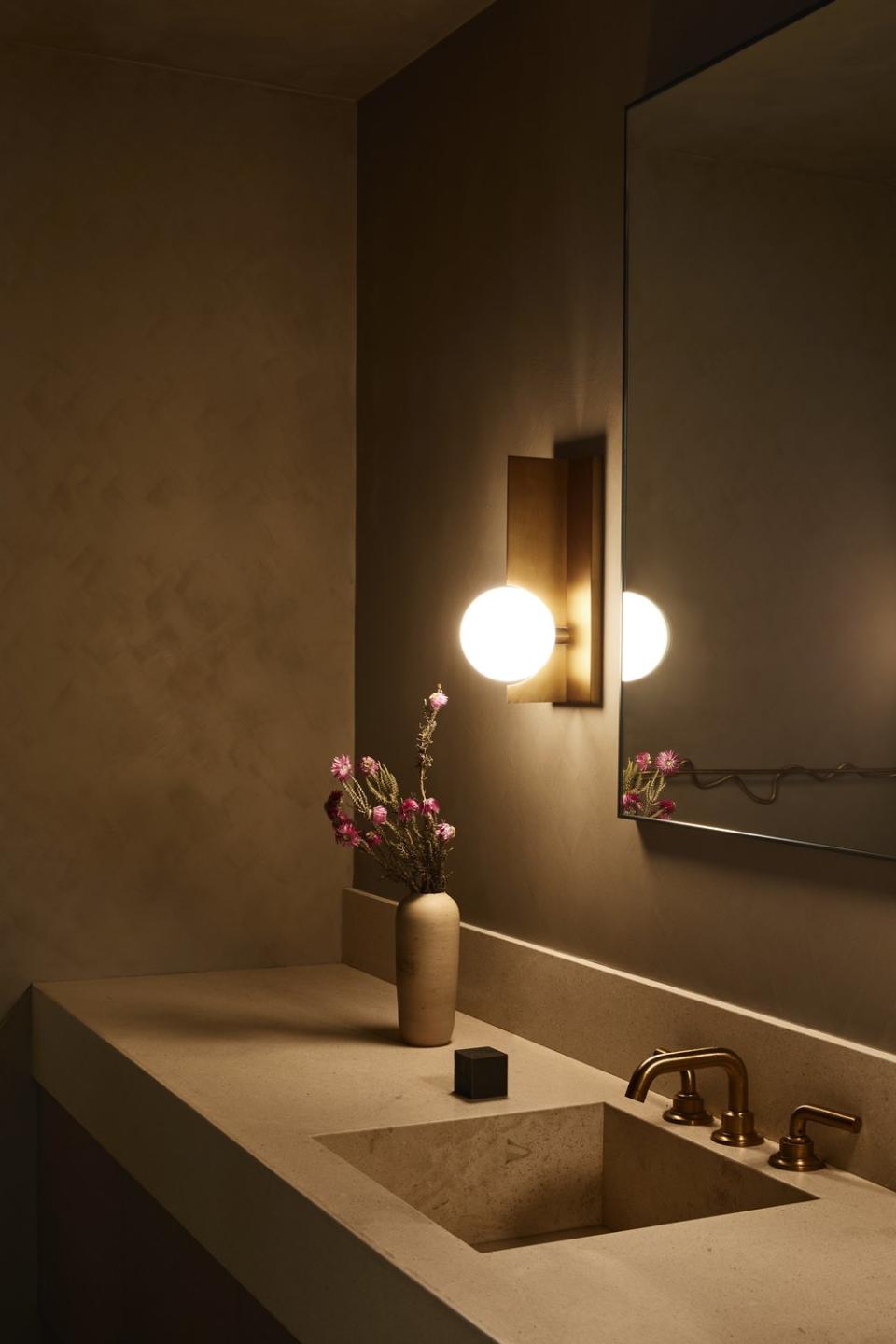 bathroom with stone sink and brass light