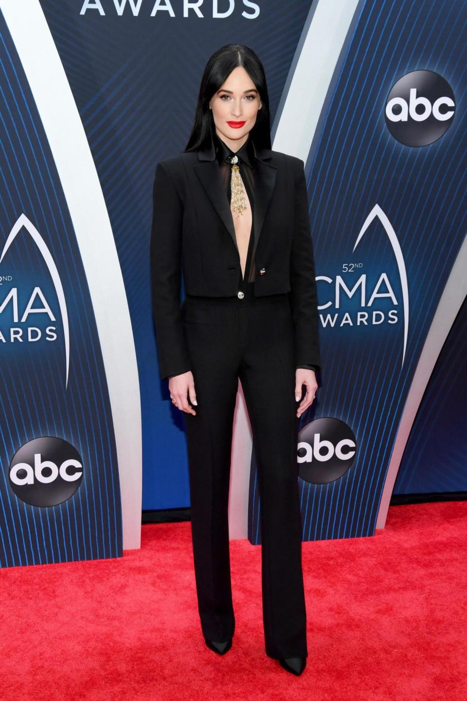 Kacey Musgraves wearing a black Versace jumpsuit with gold beading. (Getty)