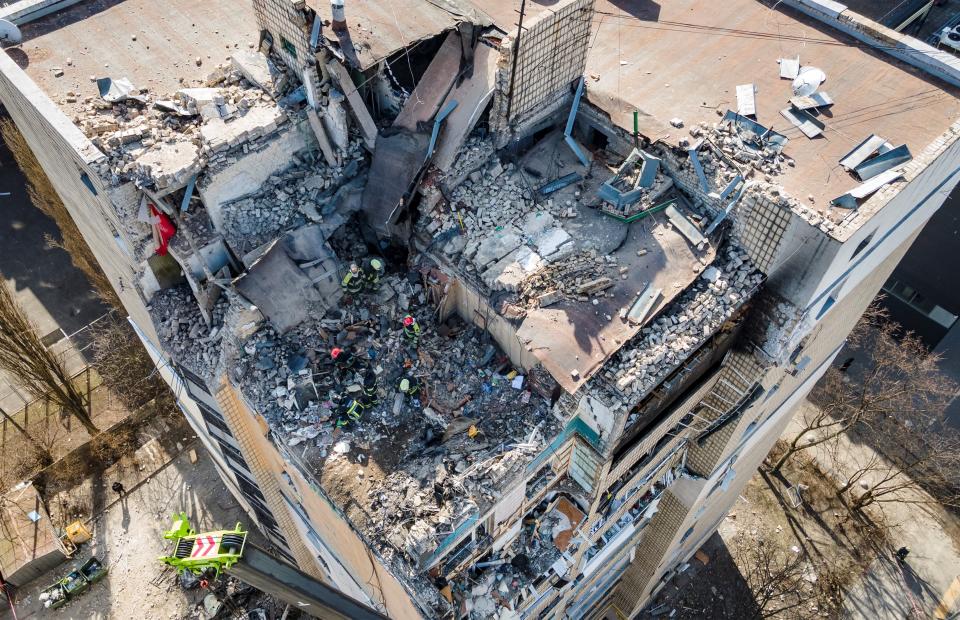 TOPSHOT - An aerial view shows firemen working in the rubble of a residential building which was hit by the debris from a downed rocket in Kyiv on March 17, 2022. - One person was killed and three injured when debris from a downed rocket hit a Kyiv apartment block, as Russian forces press in on the capital, emergency services said. Russian troops trying to encircle Kyiv have launched early morning strikes on the city for several successive days, putting traumatised residents further on edge. (Photo by FADEL SENNA / AFP) (Photo by FADEL SENNA/AFP via Getty Images)