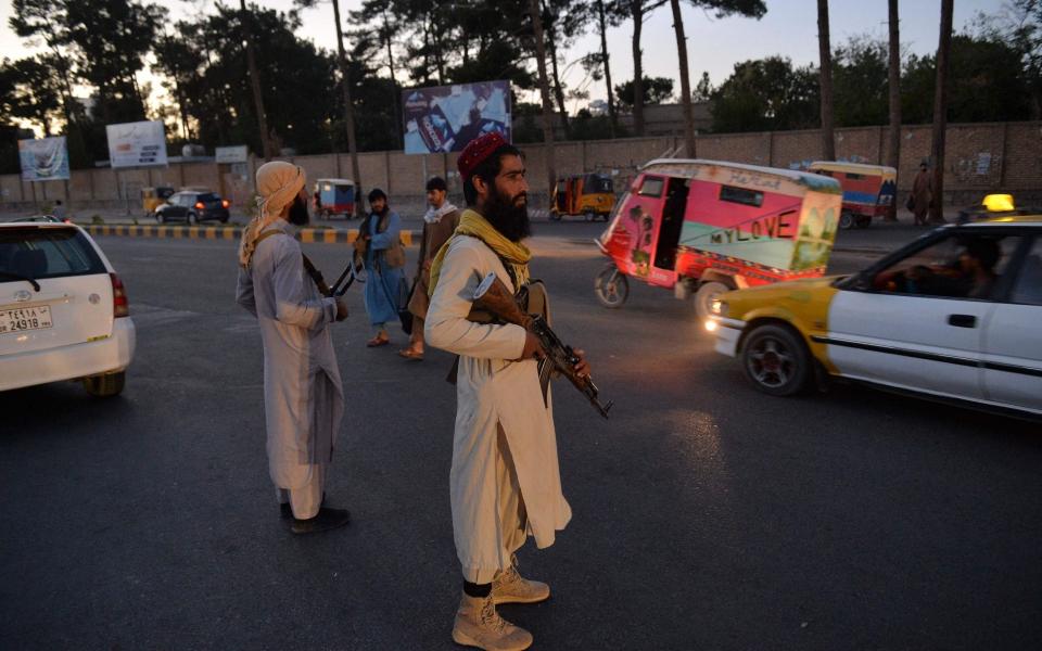 Taliban fighters stand guard along a road in Herat - HOSHANG HASHIMI /AFP