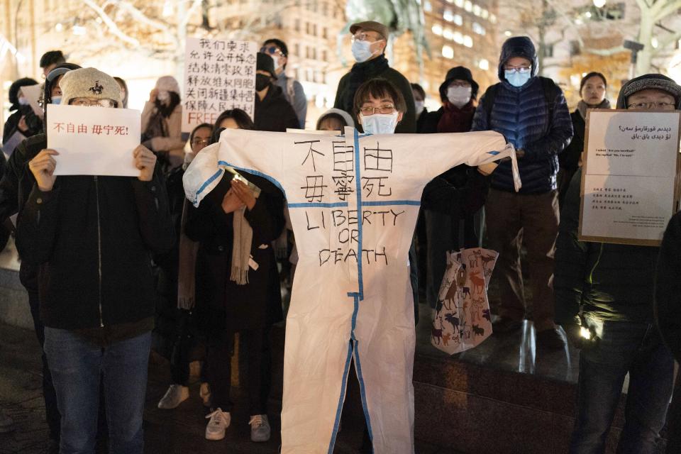 A demonstrator holds a hazmat suit as they protest at Freedom Plaza in Washington, Sunday, Dec. 4, 2022, in solidarity with the ongoing protests against the Chinese government's continued zero-COVID policies. (AP Photo/Jose Luis Magana)