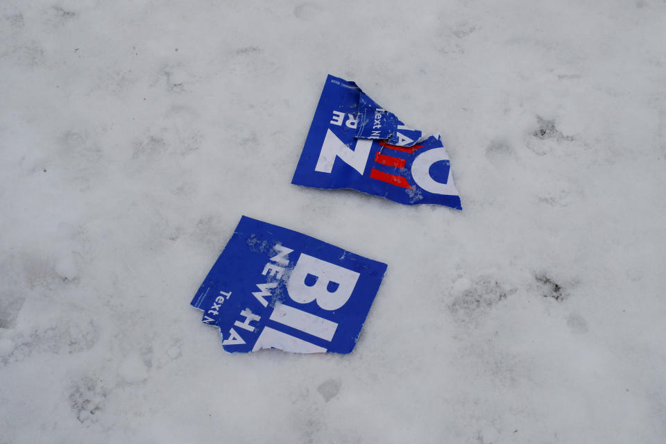 A torn campaign sign for former U.S. Vice President Joe Biden sits in the snow outside a polling site in Manchester, New Hampshire on February 11, 2020.   Brian Snyder/Reuters)