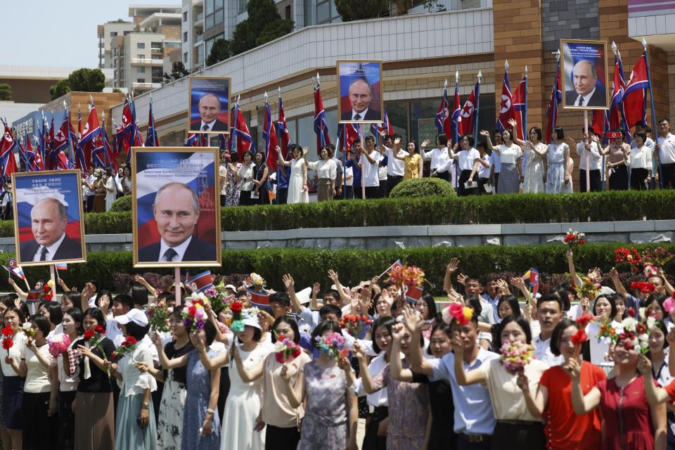 Ciudadanos norcoreanos, con retratos del presidente de Rusia, Vladímir Putin, y flores, saludan la comitiva del mandatario ruso y del líder del país, Kim Jong Un, as su paso por una calle de Pyongyang, Corea del Norte, el 19 de junio de 2024. (Gavriil Grigorov, Sputnik, Kremlin Pool Foto vía AP)