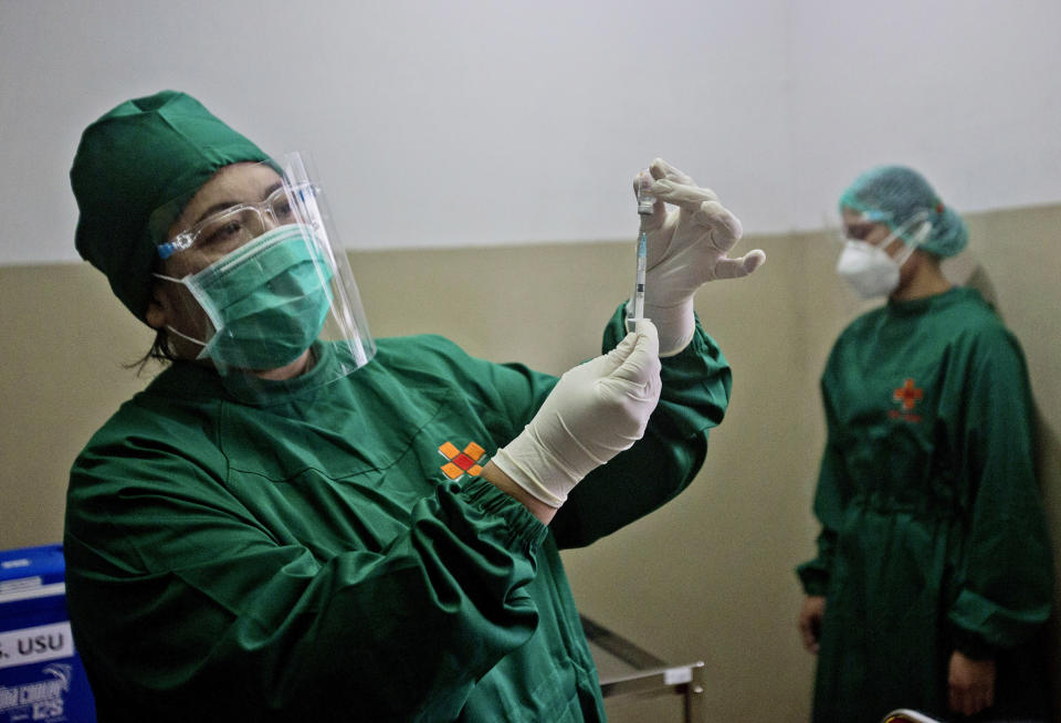 Dr. Lili Rahmawaty prepares a shot of a COVID-19 vaccine for a colleague at North Sumatra University Hospital in Medan, North Sumatra, Indonesia, Wednesday, Jan. 20, 2021. The world's fourth most populous country started giving COVID-19 vaccine to health workers and public servants last week in the first stage of a plan to vaccinate two-thirds of its population of about 270 million people — or just over 180 million people. (AP Photo/Binsar Bakkara)