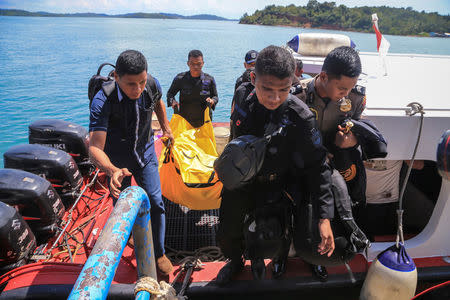 Police carry a body bag containing debris and belongings recovered from an aircraft carrying 13 police personnel which went missing on Saturday in Batam, Riau Islands, Indonesia December 4, 2016 in this photo taken by Antara Foto. Antara Foto/M N Kanwa/via REUTERS