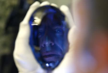 Philanthropist Maurice Ostro is reflected in his Ostro stone, the largest known blue topaz stone, as he holds it for media at the Natural History Museum in London, Britain September 27, 2016. REUTERS/Peter Nicholls