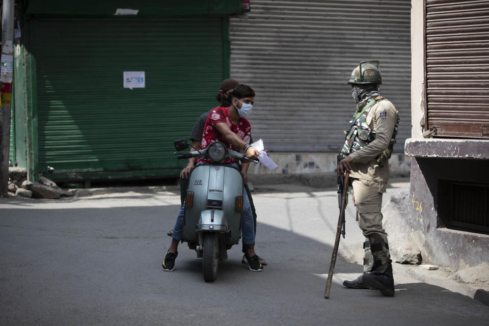 A Kashmiri man shows documents to a paramilitary soldier to cross a road during curfew in Srinagar, Indian controlled Kashmir, Tuesday, Aug. 4, 2020. Authorities clamped a curfew in many parts of Indian-controlled Kashmir on Tuesday, a day ahead of the first anniversary of India’s controversial decision to revoke the disputed region’s semi-autonomy. Shahid Iqbal Choudhary, a civil administrator, said the security lockdown was clamped in the region’s main city of Srinagar in view of information about protests planned by anti-India groups to mark Aug. 5 as “black day." (AP Photo/Mukhtar Khan)